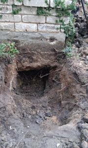 image showing the excavation of a 3x3 foot access hole next to a residential foundation for sewer repair.